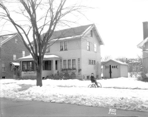 Howard D. Piper house, 1917 Commonwealth Avenue, with snow on the ground and a child riding a tricycle on the sidewalk.