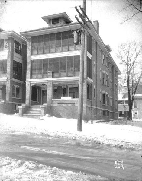Three-story apartment house, 148 E. Gorham Street, with snow on the ground.