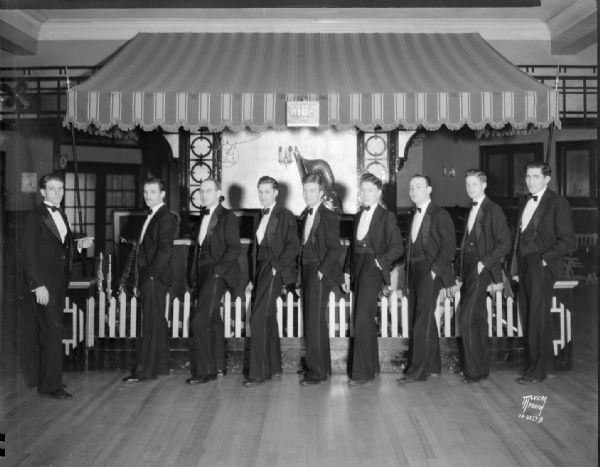 Men in the orchestra are standing in a row posing at the Chanticleer ballroom.