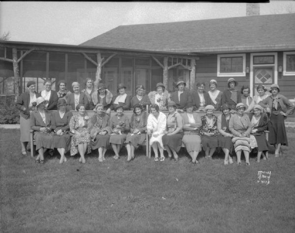 Outdoor group portrait of women golfers sitting and standing and wearing street clothes at the Blackhawk Country Club house, 3606 Blackhawk Drive.