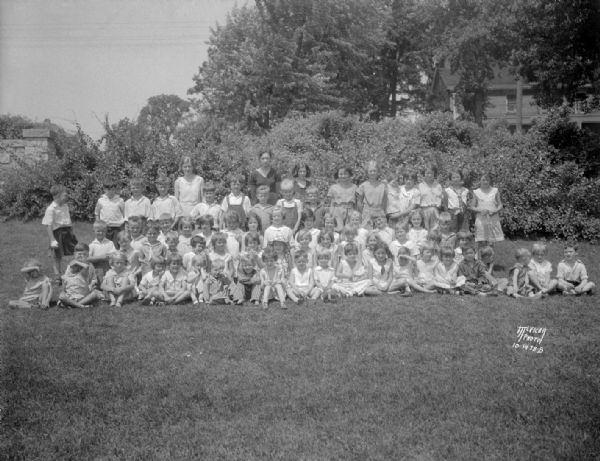 Group portrait of children who attended the Dudgeon School summer playground program, and their director Cornella Krings, at Duck Pond, Nakoma.