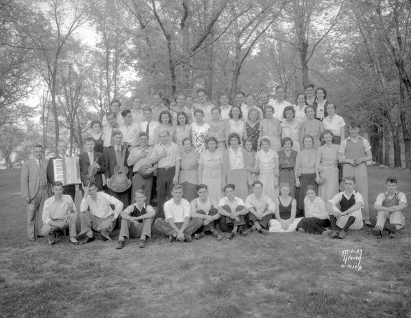 Group portrait of West High School students (Phi Bi Chem ?) on a picnic at Olin Park. Three students are holding musical instruments.