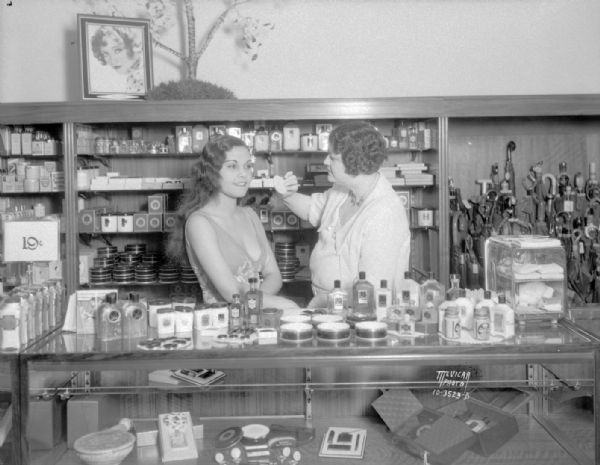 Reri (Anne Chevalier), Tahitian star of the Fanchon and Marco "Tahiti" show at the Orpheum Theatre, being made up by Max Factor representative, Mabelle Hege, in the cosmetics department at Manchesters.