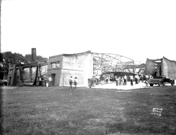 People looking at the ruins of the Royal Airport hangar and office after a fire. Viewed from the southwest.