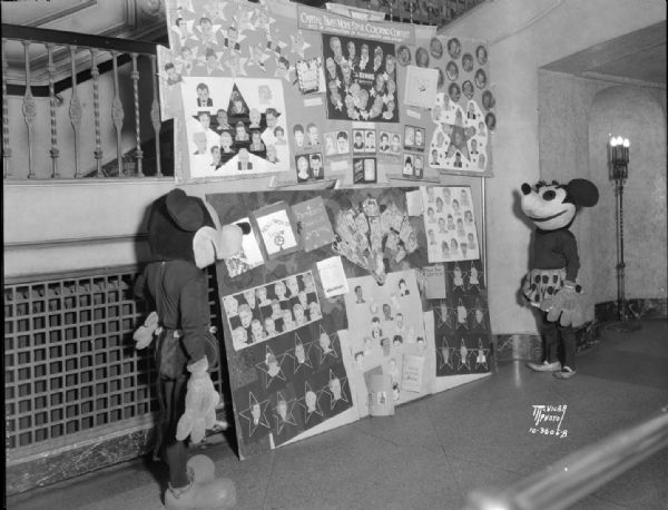 Mickey Mouse and Minnie Mouse viewing contest entries for <i>The Capital Times'</i> recent Movie Star Coloring contest held in celebration of RKO's Greater Show Season, appearing in Fanchon & Marco's "Mousical Revue."