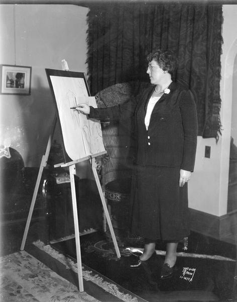 Margueretta Dalton, 1314 Randall Court, student of Prof. Stebbins' life class in drawing, shown standing at easel, drawing with charcoal.