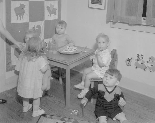Children's birthday party. Taken for Mrs. Louis McGann. Shows children's room decor, small table with five children sitting around it.