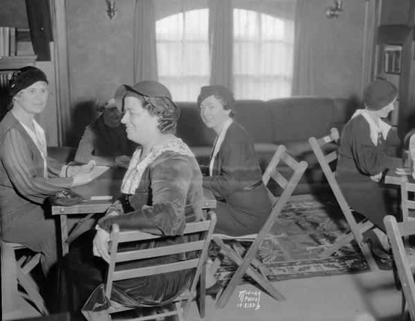University League benefit bridge tea at University of Wisconsin Pres. Glenn Frank's home, 130 N. Prospect Avenue, senior division in the President's study on the third floor. Left to right around the table are Ruth Kemmerer, Olive Reis, Louise Buerki, and Vivian Wilkie.