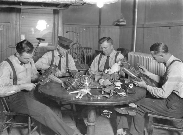 Fire fighters repairing toys at the Central fire station, 18-20 South Webster Street. The three men on the left are Charles Tomcany, Clark B. Jenkins, and James Williams.