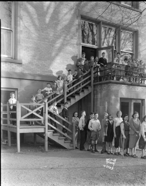 Crippled children in a fire drill at Longfellow School, 1002 Chandler Street. Greenbush Neighborhood. "They emerge in two orderly files, one for the most able and another for those hampered with greater injuries.  Those unable to walk are carried downstairs by the teachers."