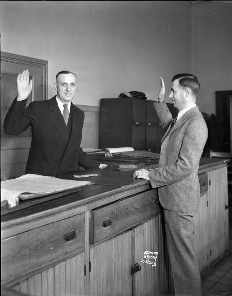 Mayor James R. Law standing at the City Clerk's counter taking oath of office being administered by the city clerk, John Fahning.