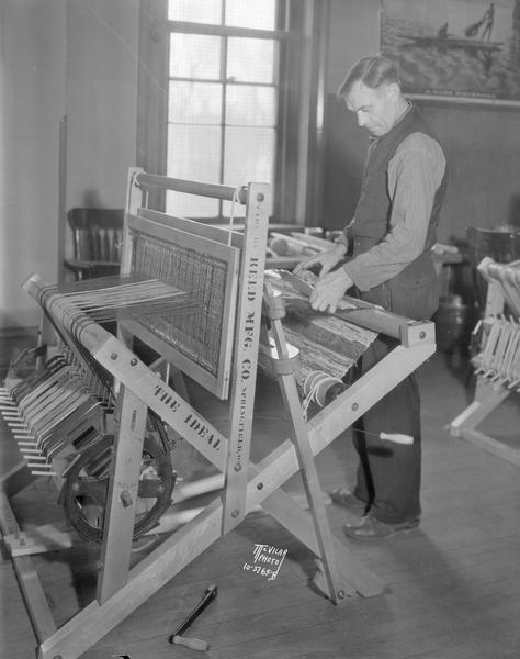Man weaving at Reed Manufacturing loom, in the Vocational School crafts class at Brayton School, 301 E. Washington Avenue.
