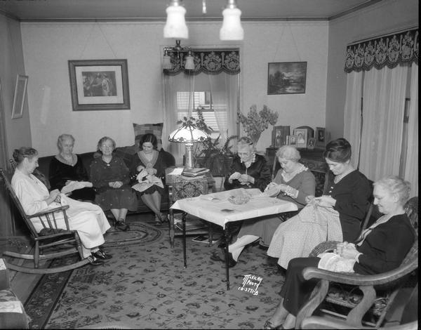 Eight women, members of Section 1 of the First Congregational Church, sewing for the Red Cross in the home of Joseph and Augusta C. Steinbach, 509 S. Randall Avenue.