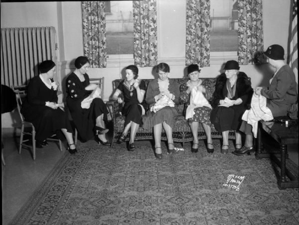 Seven women from the Social Service Department of the Woman's Club sewing for the Red Cross in the lounge of the Woman's Club, 240 W. Gilman Street.