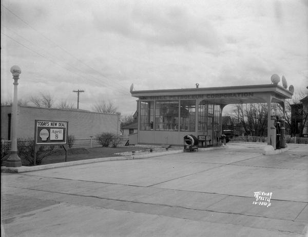 Shell Petrolium Corp. gasoline station, at the corner of Vilas and 401 S. Park Street. There is a "Today's New Deal" poster announcing a forthcoming promotion.