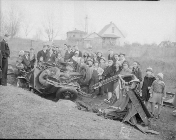 Train-car crash scene. Shows demolished automobile and large group of onlookers at Milwaukee Road, Fair Oaks railroad crossing. The driver, Miss Lena Schmidt was killed.