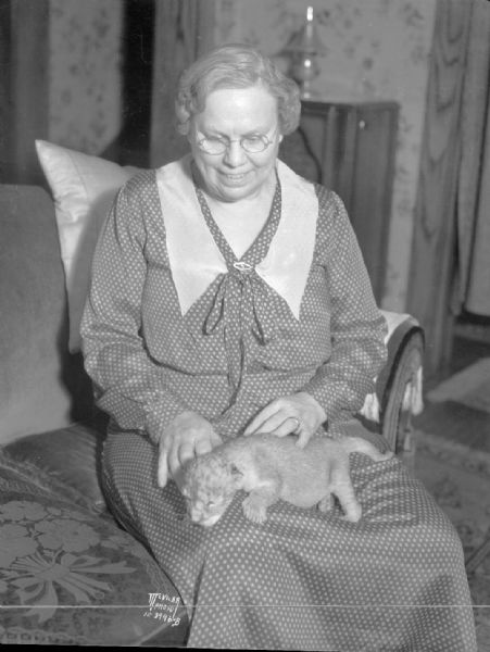 Portrait of Mrs. Emma Winkelman holding a lion cub on her lap.