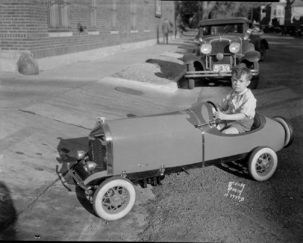 Bobbie Thorpe is sitting in "Madison's smallest real car, a National Junior Racer" to be given away to the child with the most "votes." Votes can be obtained by buying Capitol Theatre tickets, Phillips 66 gas and products and Fiore Oil Co. oil burners.
