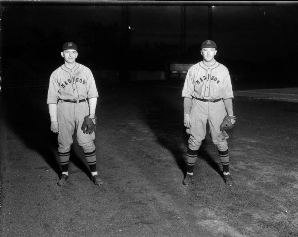 Outdoor portraits of two Madison Blues baseball players in uniform with baseball gloves on left hands.