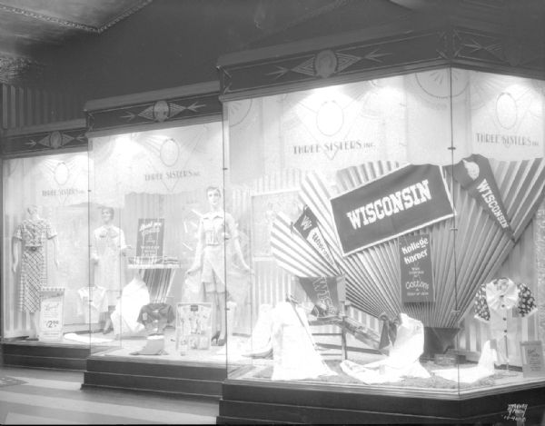 University of Wisconsin window display at the Three Sisters store, 27 S. Pinckney Street, Tenney Building, with banners, mannequins and clothing. Art deco style building detail.