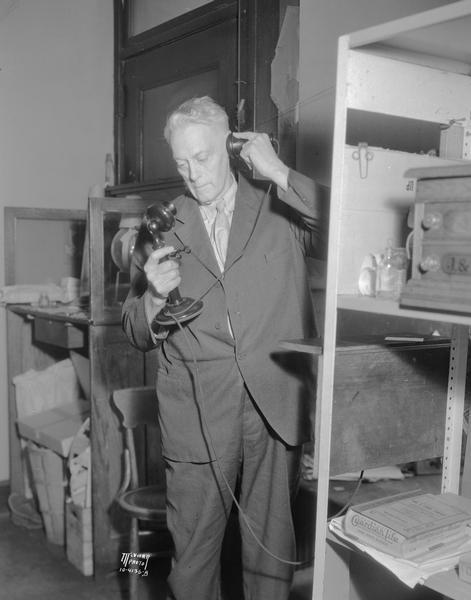 Samuel E. Capron, using a telephone while re-enacting the call he made to <i>The Capital Times</i> to announce Pres. Warren G. Harding's death in 1923.