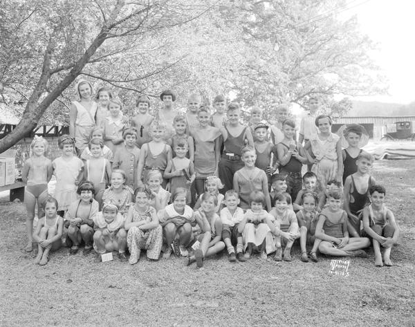 Group portrait of Kiddie Camp children on their last day of camp, with camp buildings in the background, 3910 Mineral Point Rd.