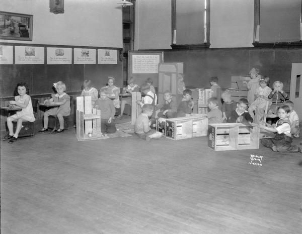 Large group of children making orange crate furniture at Hawthorne School, 216 Division Street. Activities include sawing and hammering.