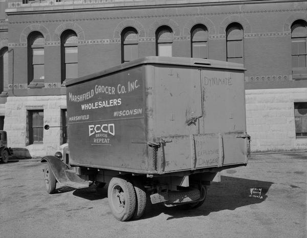 Rear of International delivery truck. "Ecco Food Products" and "Marshfield Grocer Co. Inc. Wholesalers Marshfield Wisconsin." Taken next to Dane County Courthouse? This truck was driven by Frank McCorison, accused of first degree murder, and Harvey McCorison, charged with assault, in the death of Gunder Felland, a Dane county farmer participating in the milk strike.