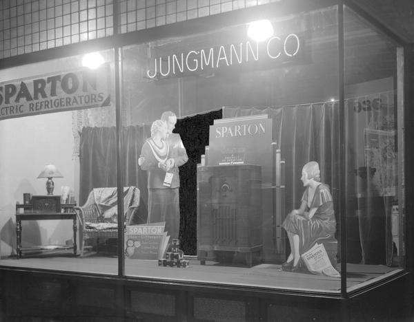 Jungmann Co. display window with cardboard cutouts of a man and two women admiring a Sparton floor model radio, 326 W. Gorham Street.