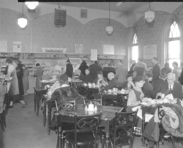 Interior of Piper's Garden Cafeteria, 120 East Mifflin Street, showing people in the cafeteria line, and sitting at tables eating.