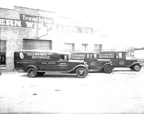 Monona Distributing Co. three delivery trucks in front of H.E. Meier garage, 18 N. Charter Street. Sign on trucks reads: "Hellmann's Mayonnaise, Quinlin's Pretzels, Grocer Specialties."