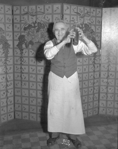 Bartender Fritz Genske, "the dean of Madison bartenders," shaking a cocktail shaker at the Elks Club, 120-124 Monona Avenue. (Now known as M.L. King Jr. Boulevard.)
