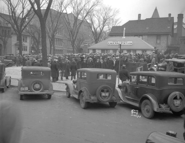 Hundreds of men are crowded around the newly opened Dane County C.W.A. pay station, at the corner of West Dayton and North Carroll Streets.