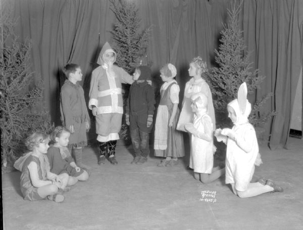 Saint Andrews Church children's Christmas play cast. In a scene from "Santa and the Little Girl." Left to right: Betty Jane Wilson, Margot Smith, Joseph Bloodgood, Arnold Simon as Santa Claus, Mary Allison Schmidt, Carolyn Hicks, Joanne Supernaw, Ellen Shaw Garrison, and Jill Bloodgood.