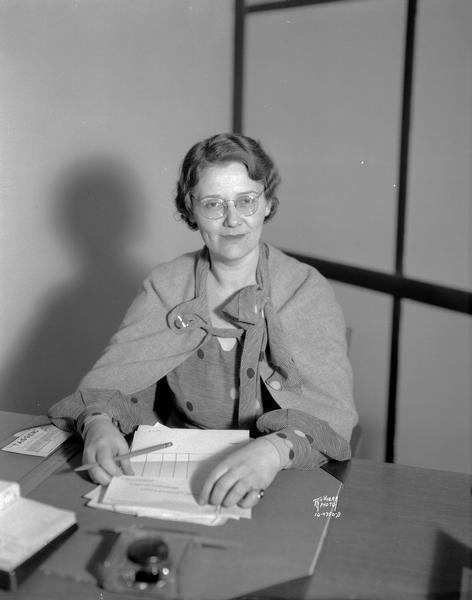 Portrait of Miss Gertrude Deniger sitting at her desk. She is executive secretary of the Madison division, Wisconsin Transient Bureau, 133 East Wilson Street.