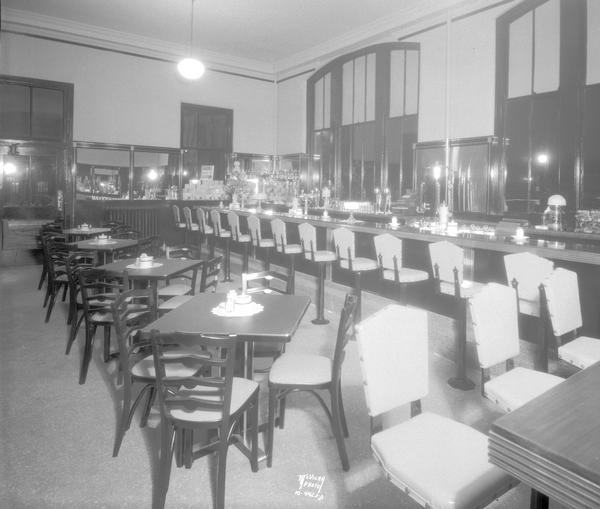 Interior of the Union News soda grill at the Chicago and North Western railroad depot, 219 S. Blair Street, from the entrance, showing lunch counter and dining tables.