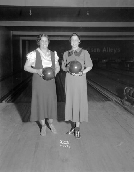 Ella Burmeister and Avis Kidd, holding bowling balls at the Madison Alleys, 112 N Fairchild Street, winners of the women's Wisconsin state doubles bowling crown.