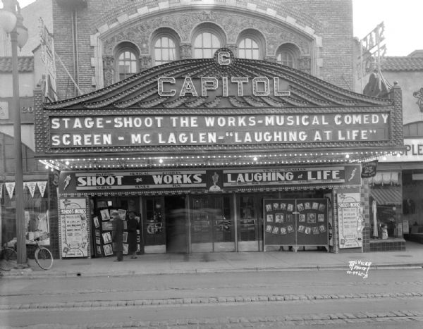 View across street towards the Capitol Theatre marquee, 209-211 State Street. The signs on the marquee read: "Stage - Shoot the Works - Musical Comedy," "Screen - McLaglen - "Laughing at Life."
