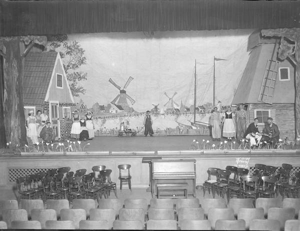 Scene from East Junior High School operetta with thirteen actors in costume on stage and Dutch / Holand scenery.