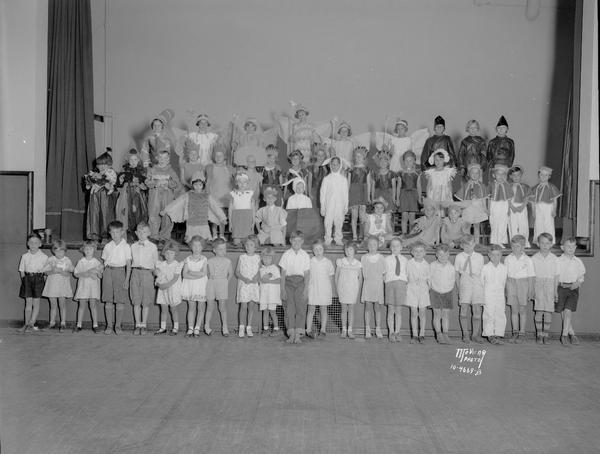 Group portrait of Franklin School students. Group portrait of children on stage who are wearing costumes, with a row of students, not in costume, standing in front of the stage.