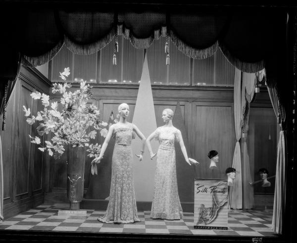 Burdick and Murray Co., 15-17-19 E. Main Street, display window featuring two mannequins in silk gowns. Head mannequins are displaying hats. A sign reads: "Silk Parade."