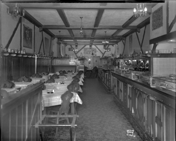 Interior of Hommel's Restaurant, 20 West Mifflin Street, with interior decor reflected in the food counters, wood panelling, table settings, lighting and beer steins on display.