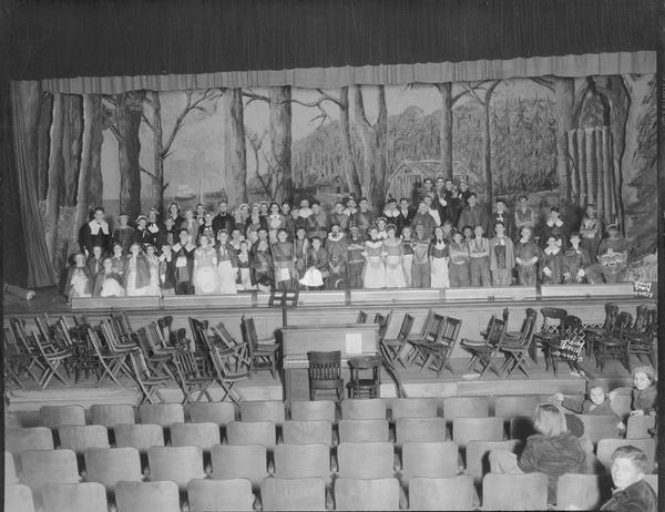 Group portrait of East Junior High School play cast, in costume on stage for the play "Plymouth Rock."