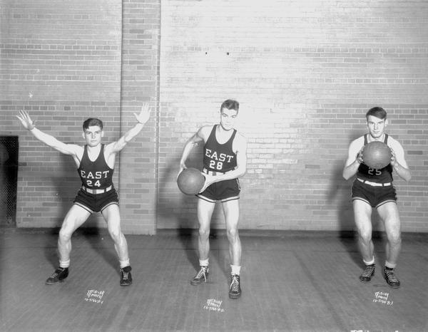 Three male East High basketball players in uniform: #24 Gilbert Hamre, #28 Earl Olson, and #25 John Barth.