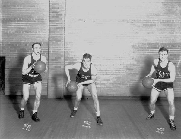 Three male East High School basketball players in uniform: Billy Schmitz #34, Pat Richter #29, and Frank Meier #31.