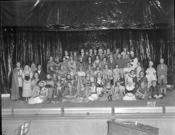Group portrait of the entire costumed cast of the operetta "Tune In" on stage at East High School. The operetta was presented by the East High A Capella Choir and Treble Clef Club.