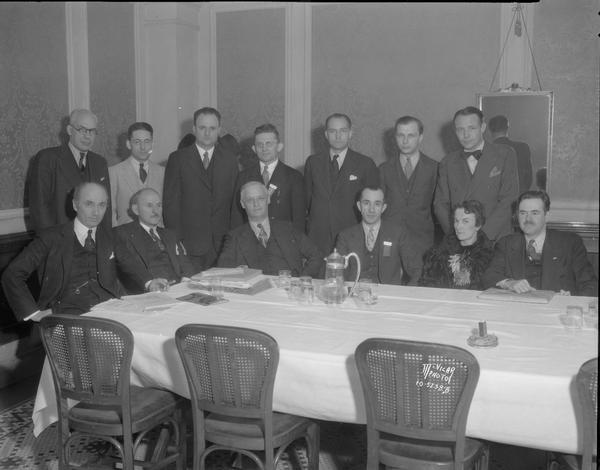 Group portrait of 13 judges and officials of the sixth annual National High School orchestra, solo and ensemble contest, at a table at the Loraine Hotel.