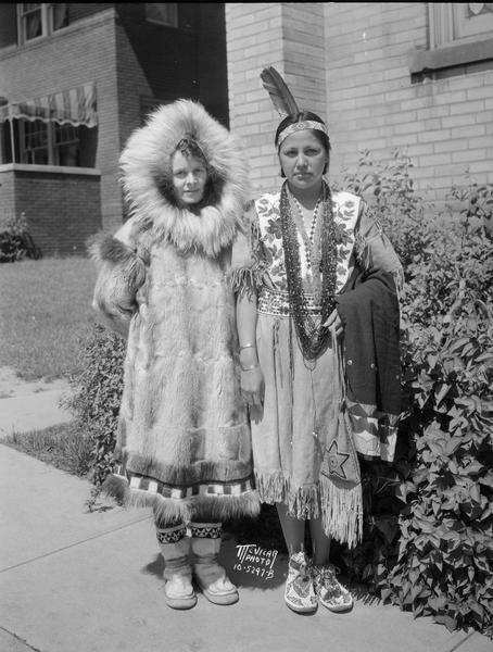 Deaconess Magdalene Klippen, of Chicago, former head of the Norwegian Lutheran Brevig Mission near Mary's Igloo, Alaska, wearing Inupiat clothing, and Lena Wabshagain, a Ho-Chunk student at the church's Bethany Indian Mission at Wittenberg, Wisconsin, posing for the Norwegian Lutheran Women's Missionary Federation meeting in Madison.