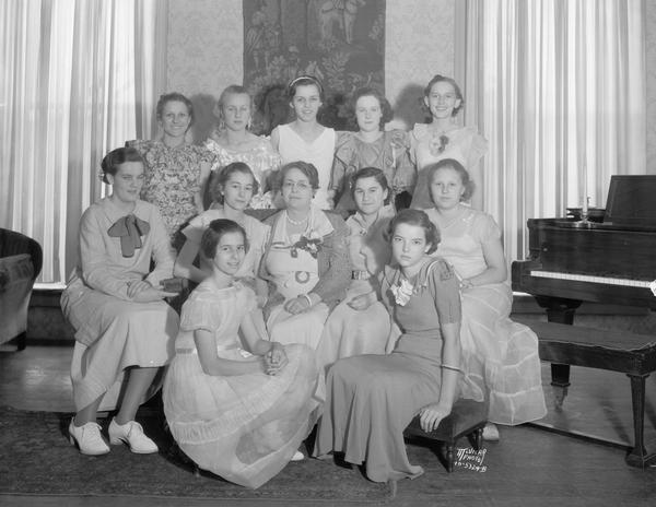 Group portrait of the cast members of the Chaminade Girls Music Club that presented a musical playlet, "The Vanquished Tempter," for the benefit of The Capital Times Family Welfare Kiddie Camp fund at the Forbes Meagher recital hall, 27 West Main Street. The play was written and directed by Virginia Michalski, assistant teacher to Marie Seuel Holst, who is sponsoring the program. Virginia is standing on the left in the back row and Marie is sitting in the middle of the middle row.