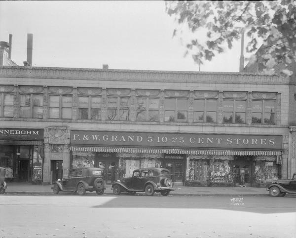 Levitan building, 15 W. Main Street (Art Deco Egyptian style), Rennebohm's drug store, 13 W. Main Street and F. & W. Grand variety store, 17 - 19 W. Main Street. The view shows angle parking on the square.